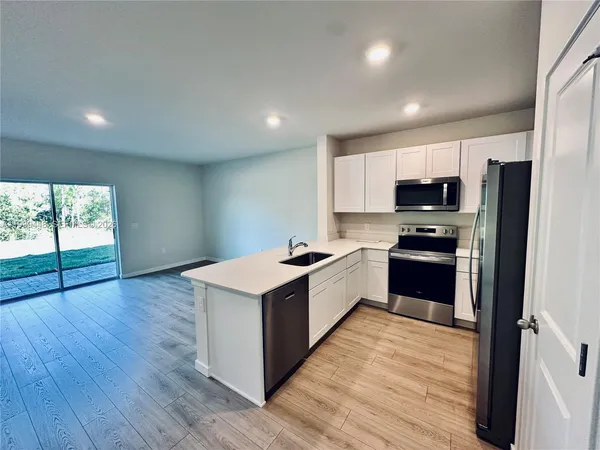 a kitchen with a refrigerator a microwave a sink and cabinets