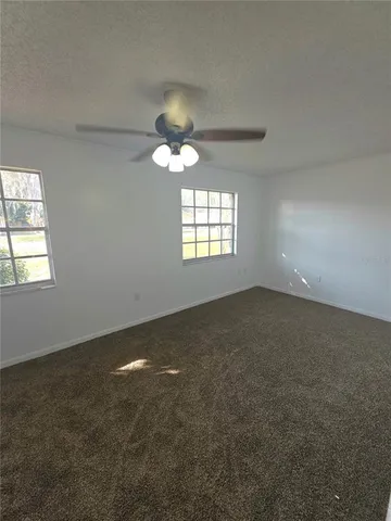 en empty room with windows and chandelier fan