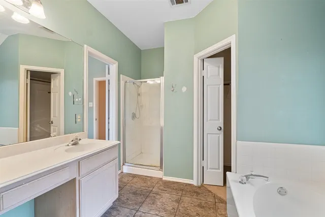 a bathroom with a tub sink shower and mirror