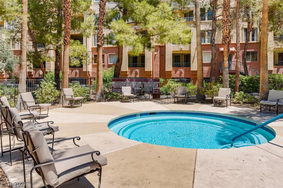 230 East Flamingo Road, Unit 334 Las Vegas, NV 89169 - Photo 33 of 37 Mature trees surround a circular sparkling pool, offering a serene outdoor retreat.