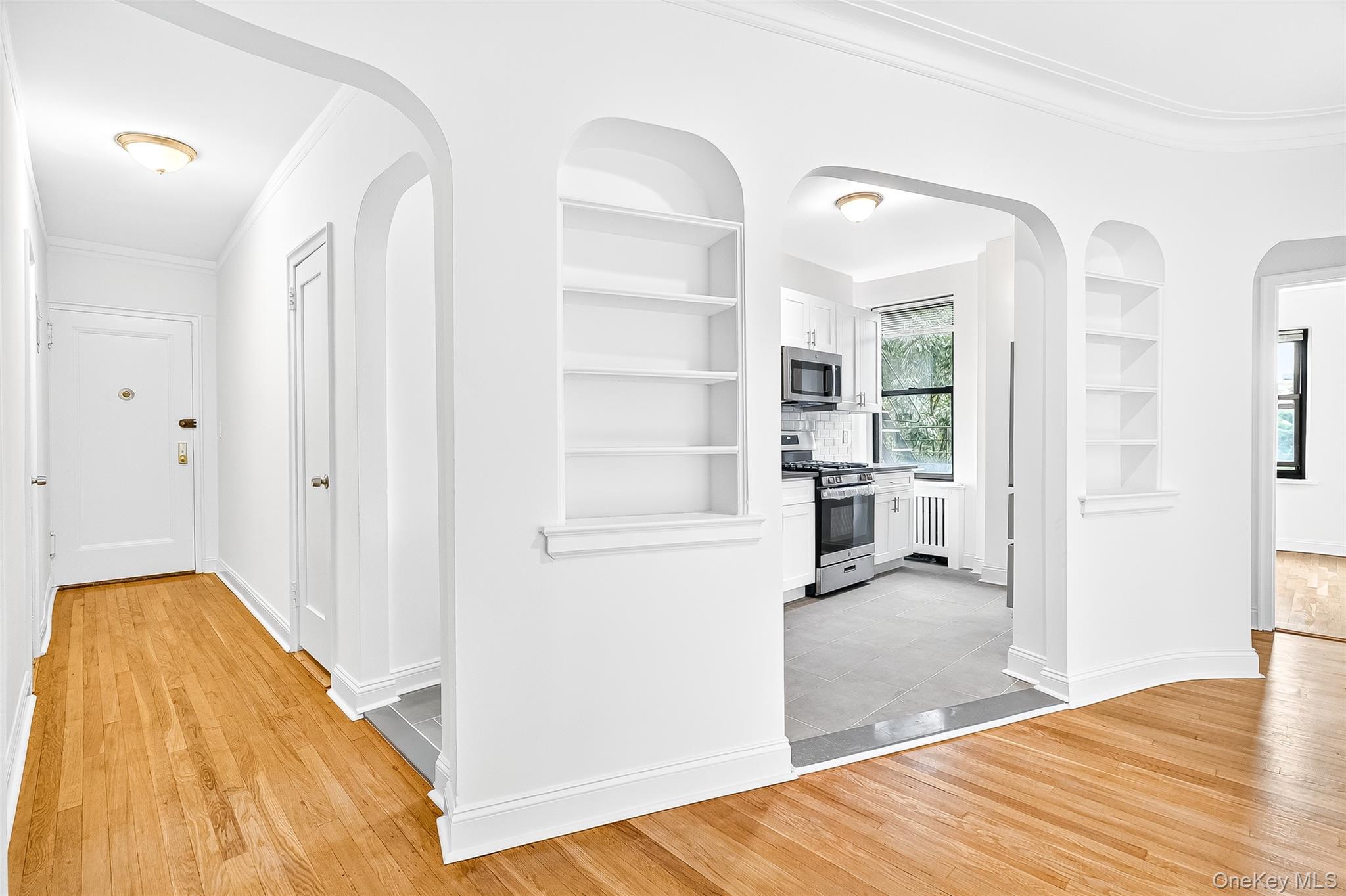 190 East Mosholu Parkway South, Unit 3C Bronx, NY 10458 - Photo 12 of 50 Hallway with arched walkways, crown molding, built in features, and light wood-style flooring