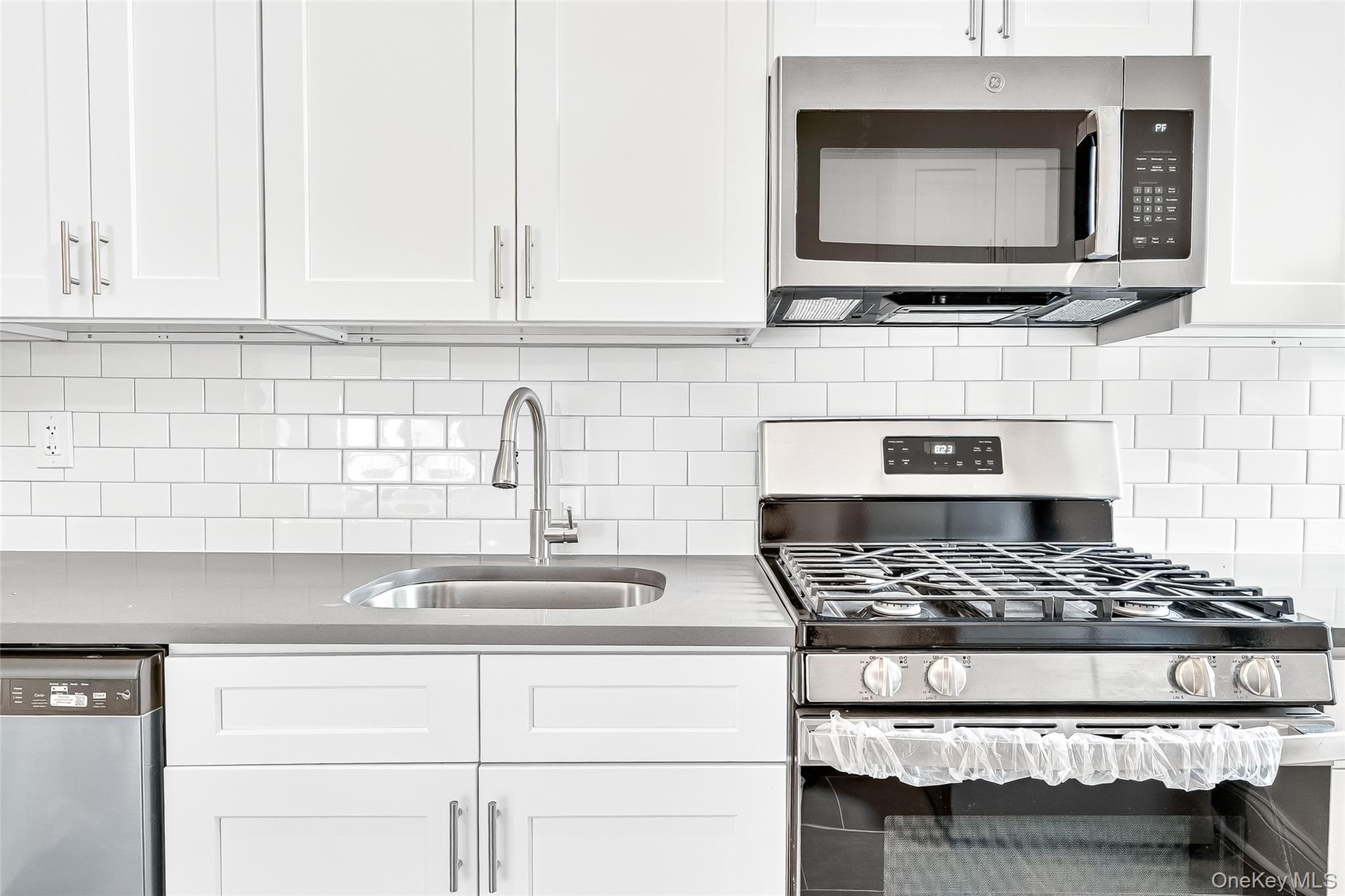 190 East Mosholu Parkway South, Unit 3C Bronx, NY 10458 - Photo 15 of 50 Kitchen with appliances with stainless steel finishes, white cabinets, and backsplash