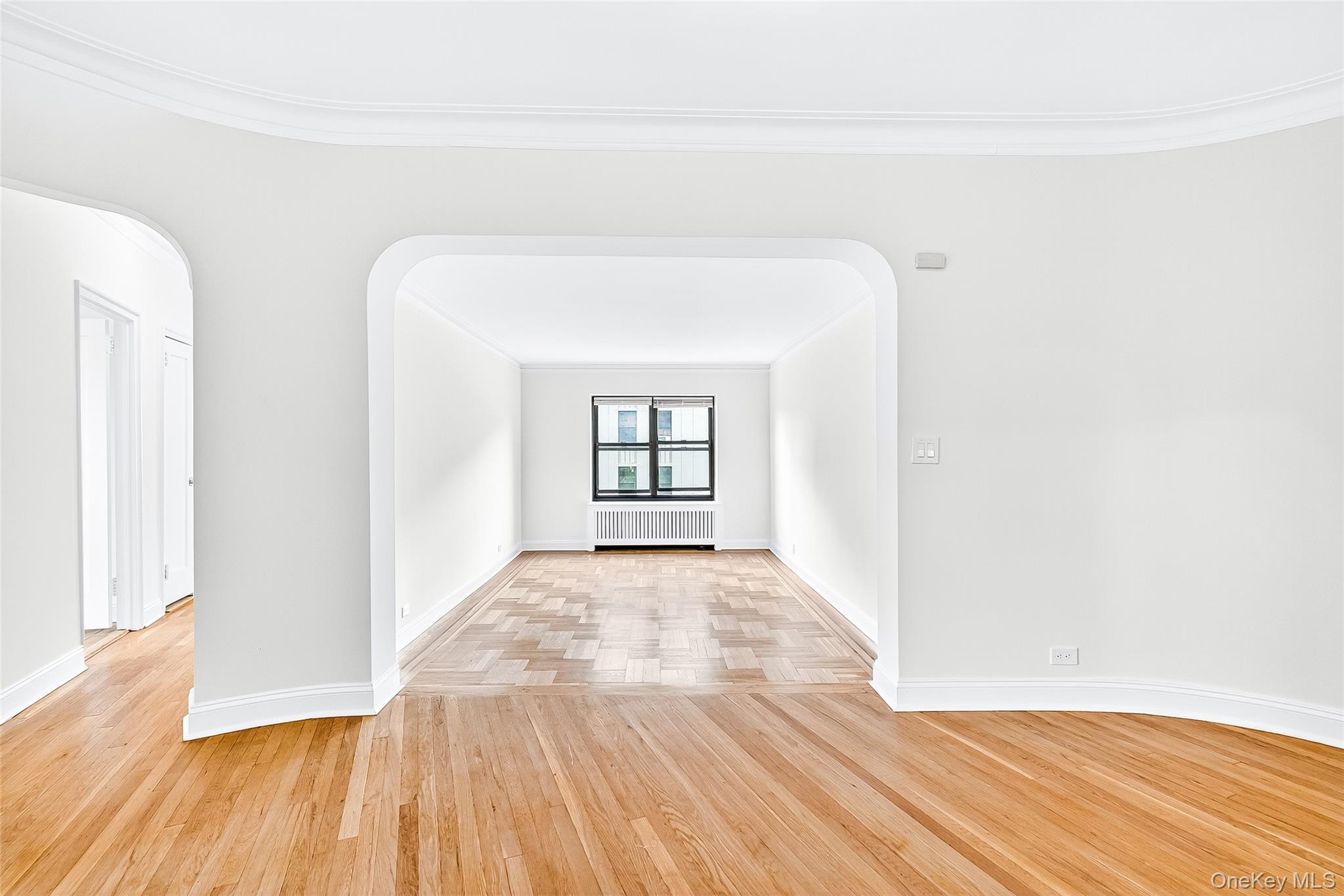 190 East Mosholu Parkway South, Unit 3C Bronx, NY 10458 - Photo 27 of 50 Unfurnished room featuring wood finished floors, crown molding, radiator heating unit, and arched walkways