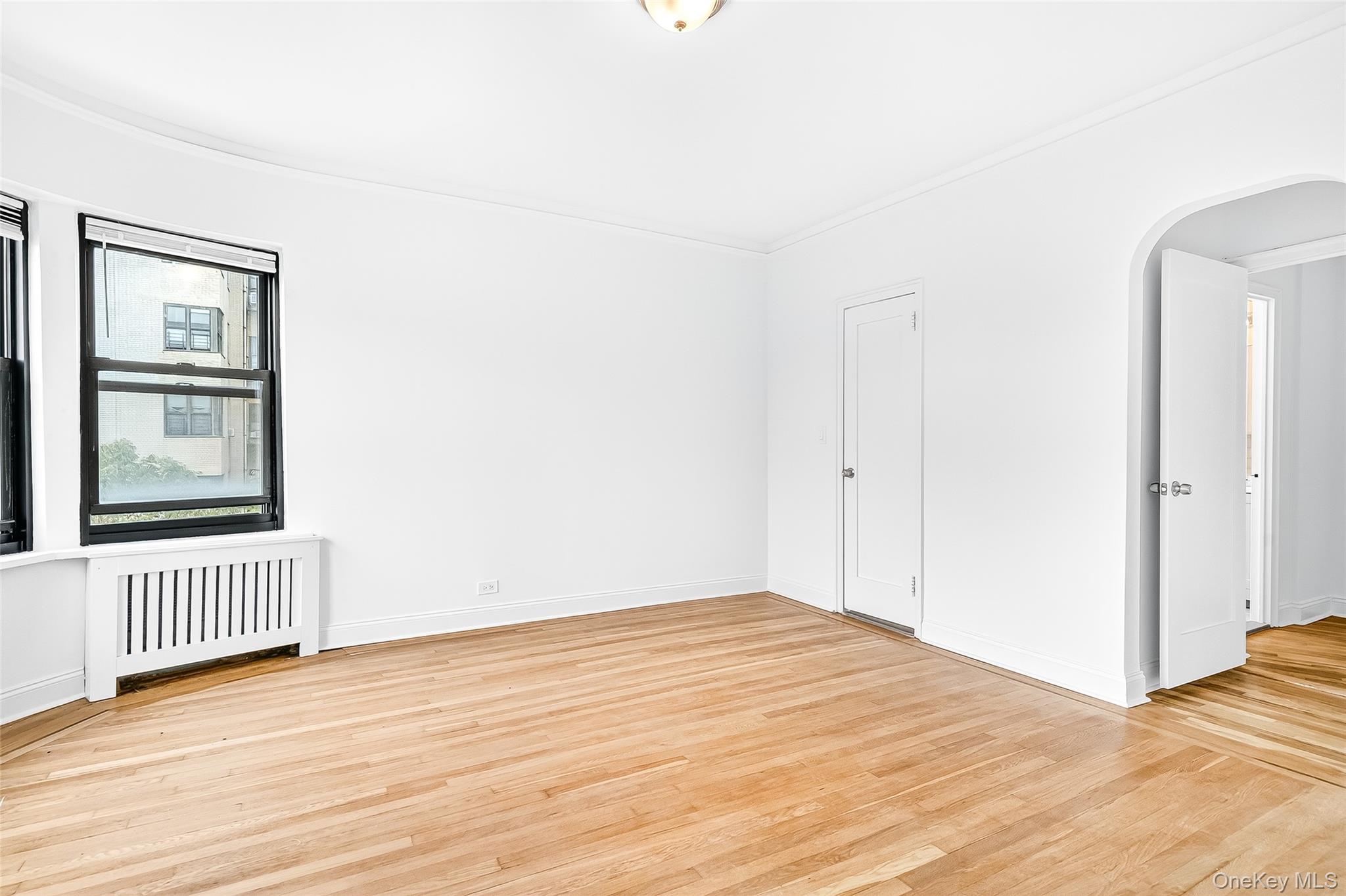 190 East Mosholu Parkway South, Unit 3C Bronx, NY 10458 - Photo 35 of 50 Spare room with radiator, arched walkways, light wood finished floors, and ornamental molding