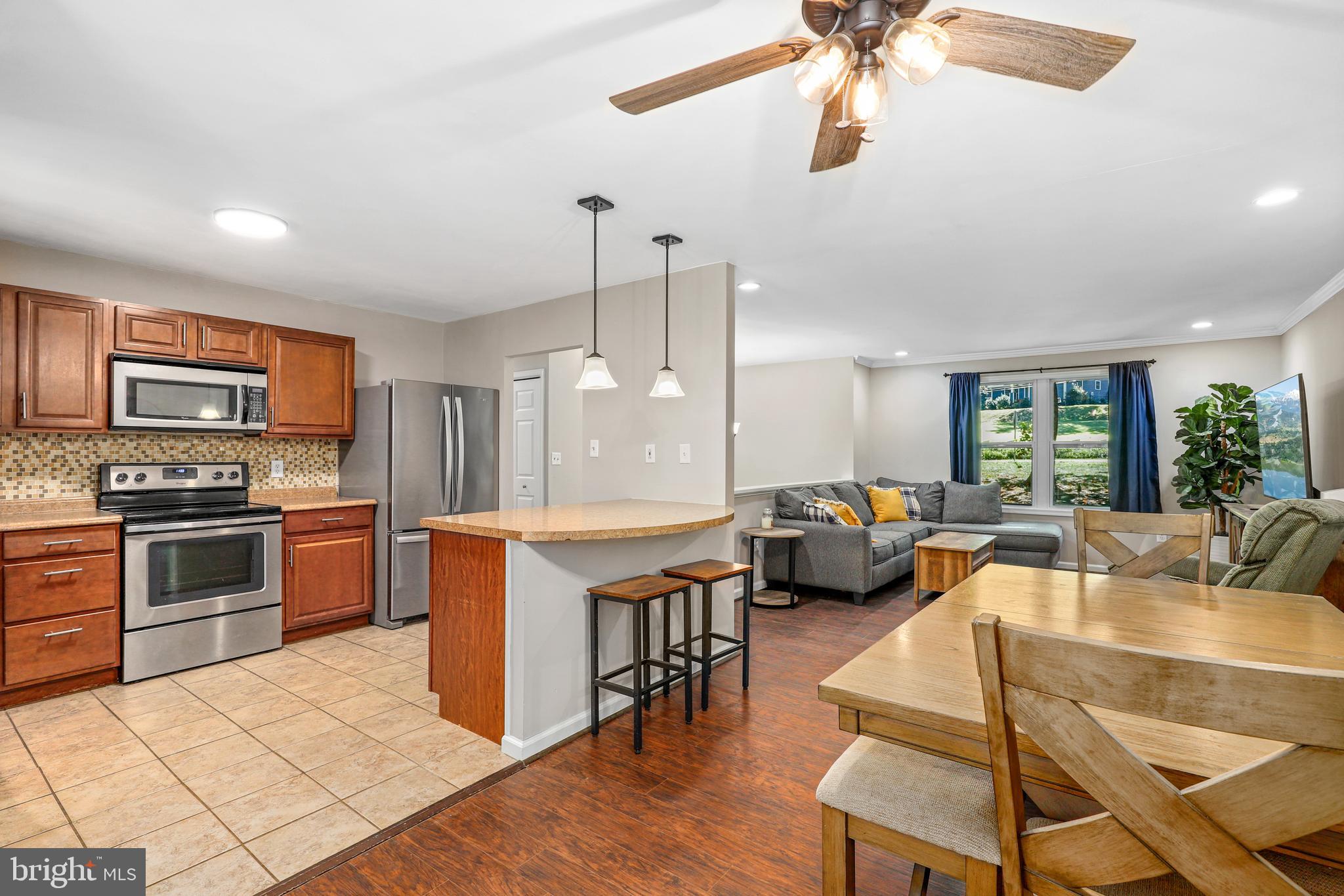 956 Wilson Road Huntingtown, MD 20639 - Photo 8 of 42 a kitchen with stainless steel appliances granite countertop a stove top oven a sink dishwasher a dining table and chairs with wooden floor