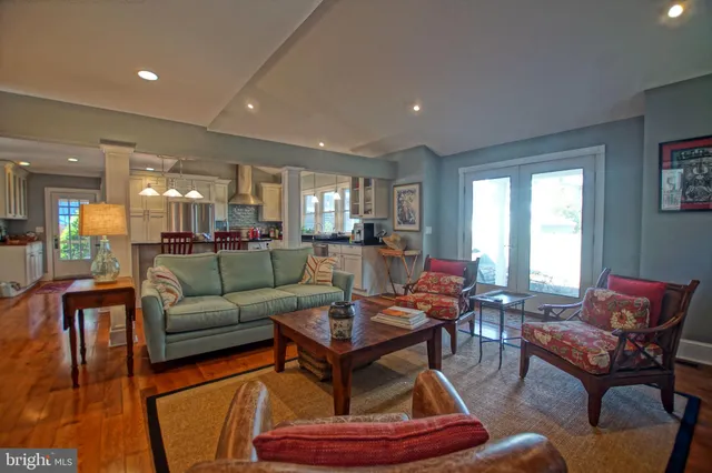 a living room with furniture and a dining table with wooden floor