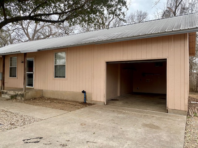 6100 Felix Avenue, Unit B Austin, TX 78741 - Photo 9 of 9 View of side of property featuring a metal roof, concrete driveway, and a garage