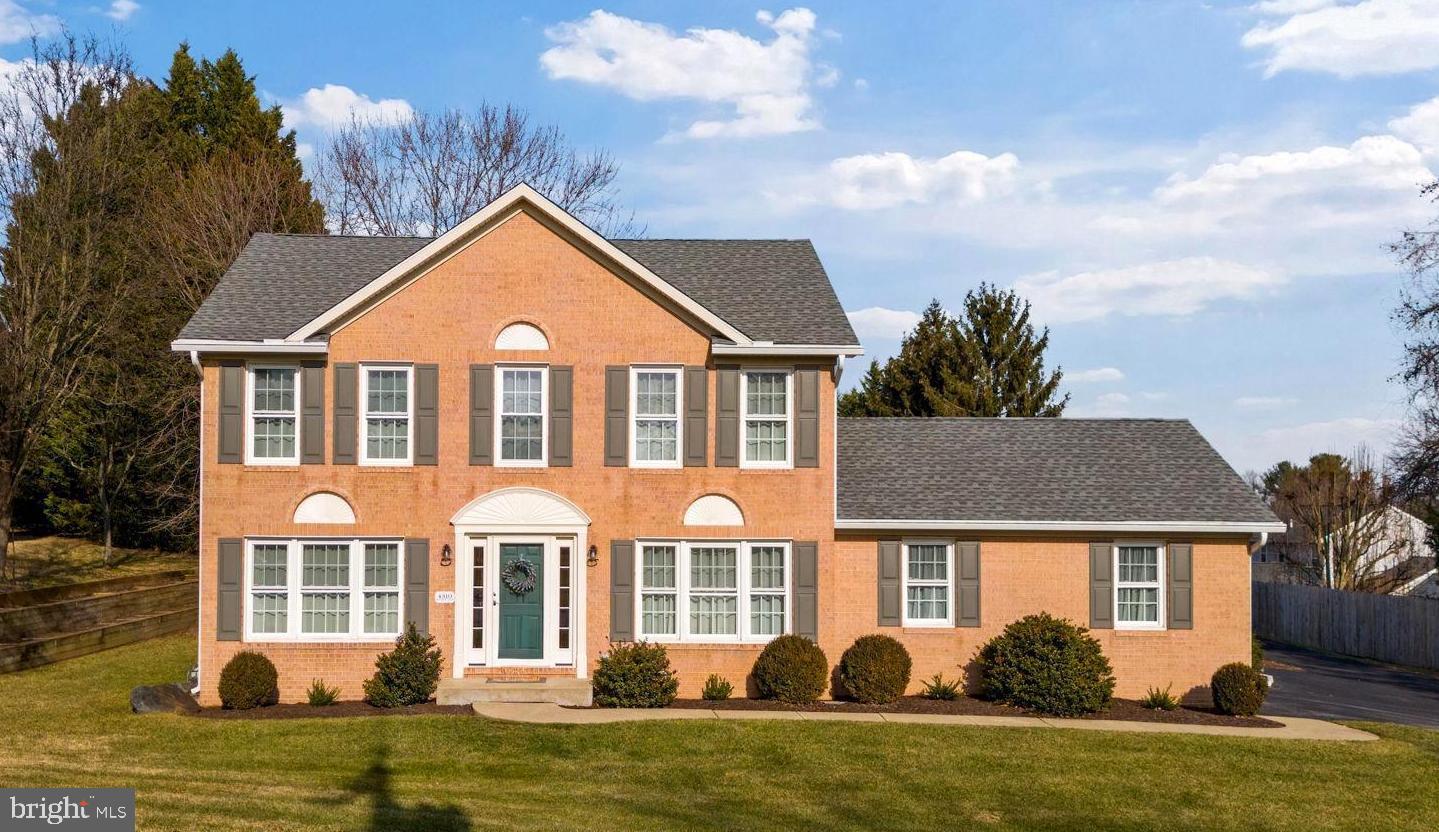 a front view of a house with garden and trees