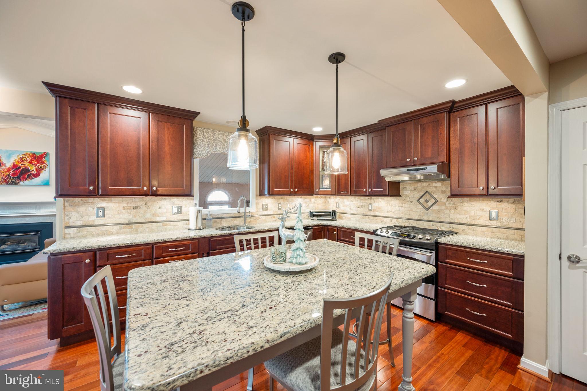 4310 Necker Avenue Nottingham, MD 21236 - Photo 13 of 56 a kitchen with stainless steel appliances granite countertop a stove a refrigerator a sink a stove and island with wooden floor
