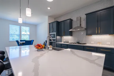 a kitchen with stainless steel appliances granite countertop a sink a stove and a refrigerator