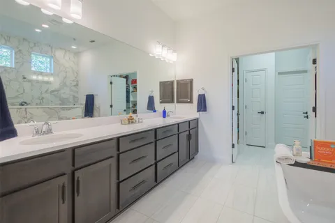 a spacious bathroom with a double vanity sink a large mirror a shower and a bathtub