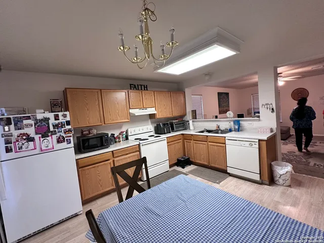 a kitchen with a refrigerator a stove a sink a dining table and chairs