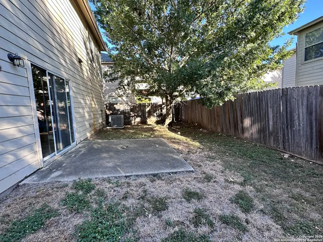a view of a backyard with wooden fence and large trees