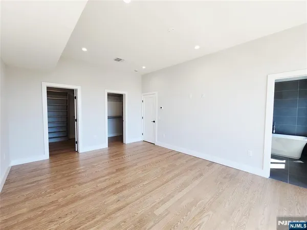 a view of an empty room with wooden floor and closet