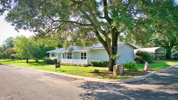 a front view of a house with garden and trees