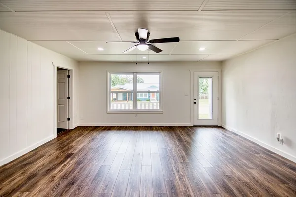 a large white kitchen with white cabinets and wooden floor