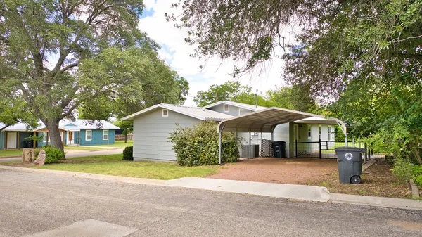 a front view of a house with a yard and large trees