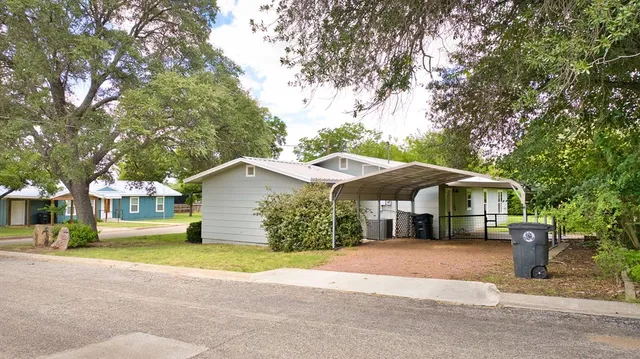 a front view of a house with a yard and large trees