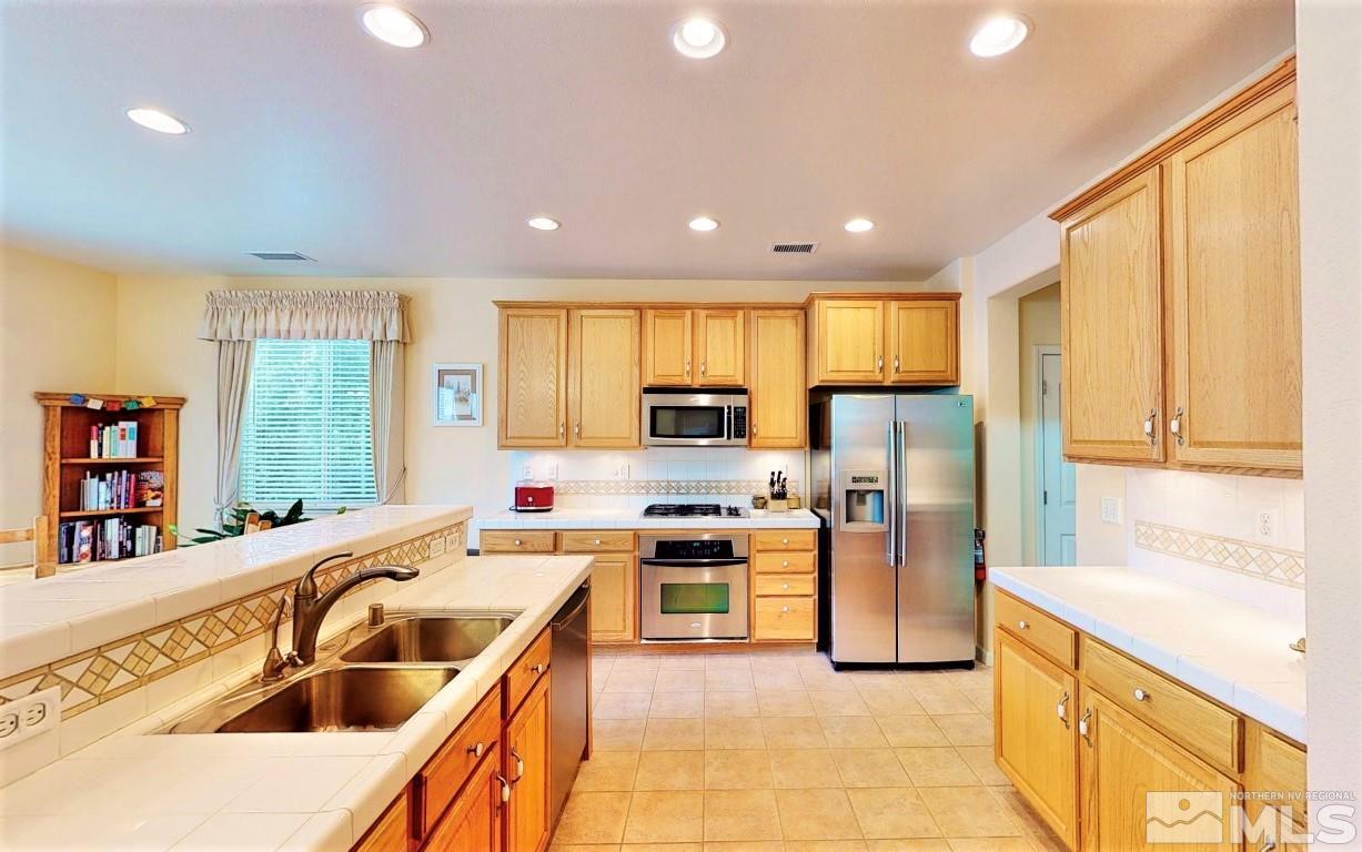 11210 Messina Way Reno, NV 89521 - Photo 7 of 29 a kitchen with stainless steel appliances granite countertop a sink a stove and a refrigerator