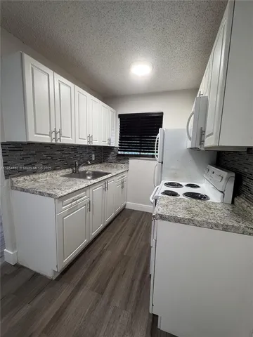 a kitchen with granite countertop wooden cabinets and white appliances