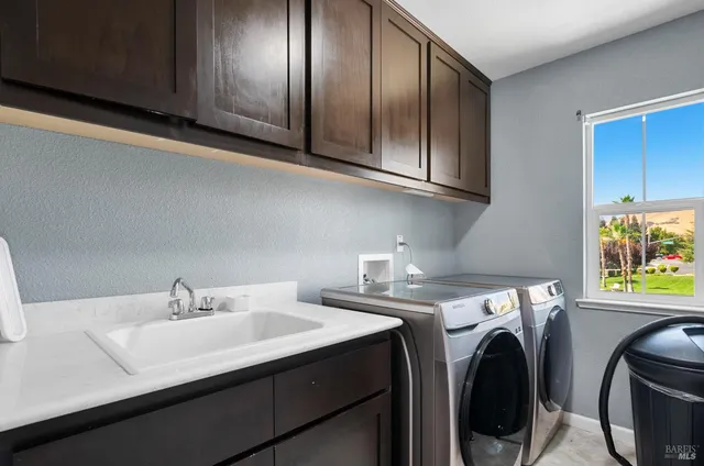 a utility room with stainless steel appliances white cabinets washer and dryer