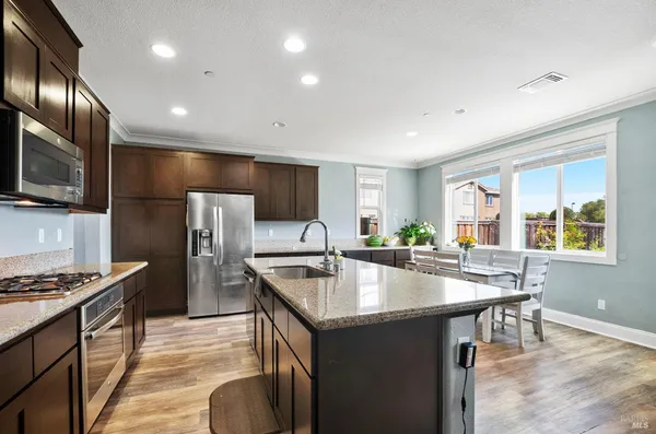 a kitchen with kitchen island granite countertop a sink stove and refrigerator