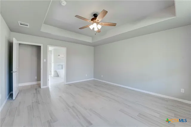 an empty room with wooden floor fan and windows
