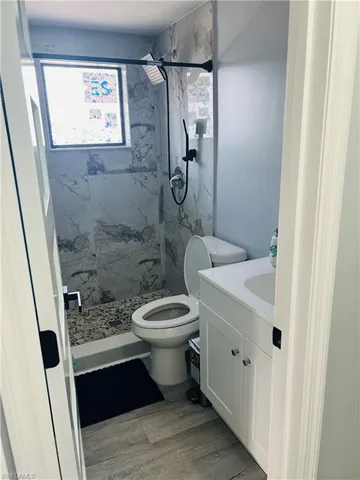 a bathroom with a granite countertop toilet a sink a mirror and shower
