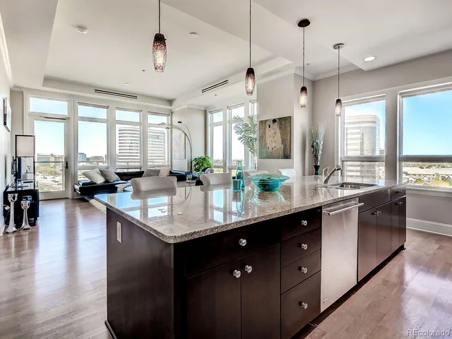 a kitchen with lots of counter top space a sink appliances and a living room view