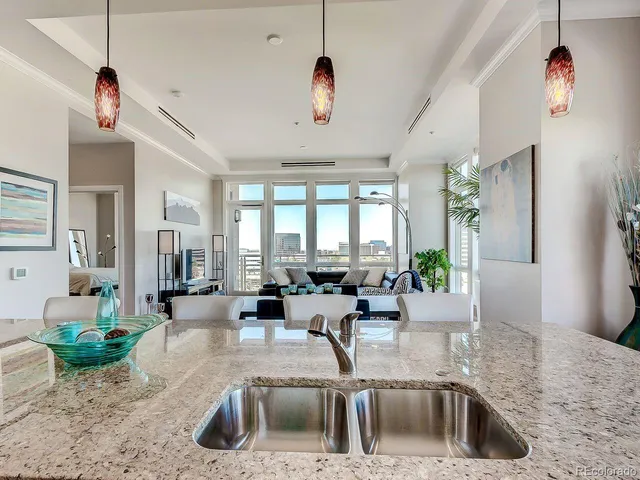 a kitchen with a sink a counter top space and living room view
