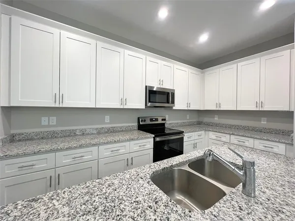 a kitchen with granite countertop white cabinets sink and stainless steel appliances