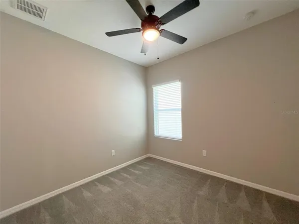 an empty room with a window and a chandelier fan