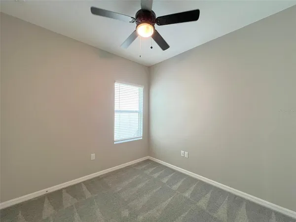 an empty room with a window and a fan