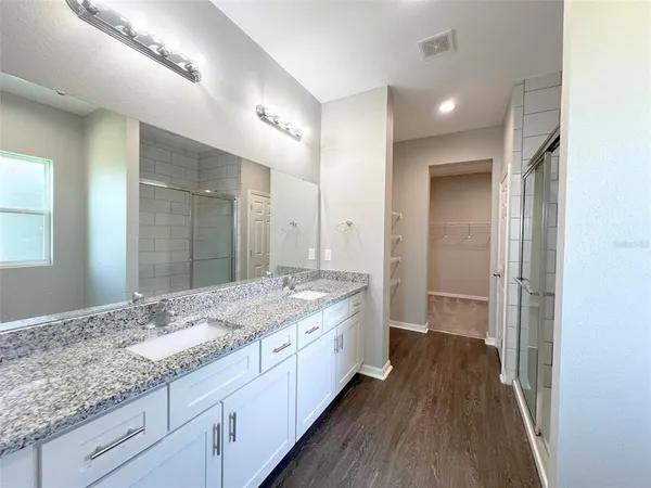 a bathroom with a granite countertop double vanity sink and mirror