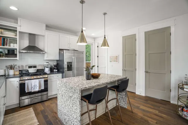 a kitchen with stainless steel appliances granite countertop a stove a sink refrigerator and a wooden floor