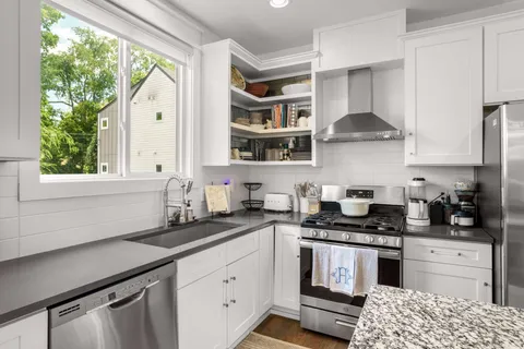 a kitchen with stainless steel appliances a sink a stove and white cabinets