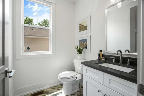 a bathroom with a granite countertop sink mirror vanity and toilet