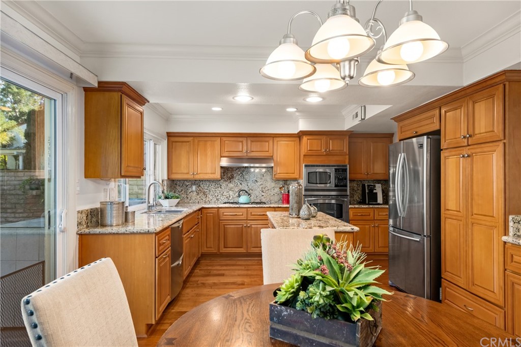 4625 Green Tree Lane Irvine, CA 92612 - Photo 15 of 51 a view of a kitchen with kitchen island granite countertop a large window cabinets a sink and stainless steel appliances