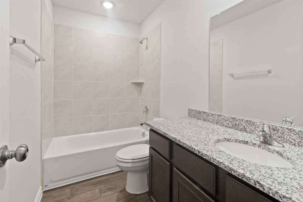 1606 Romans Road Ennis, TX 75119 - Photo 12 of 16 a bathroom with a granite countertop sink a toilet and shower