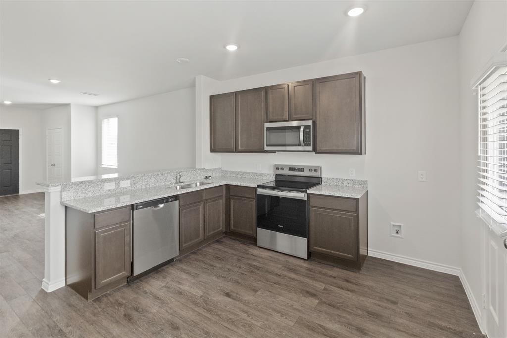 1606 Romans Road Ennis, TX 75119 - Photo 6 of 16 a kitchen with stainless steel appliances granite countertop a stove a sink and a microwave