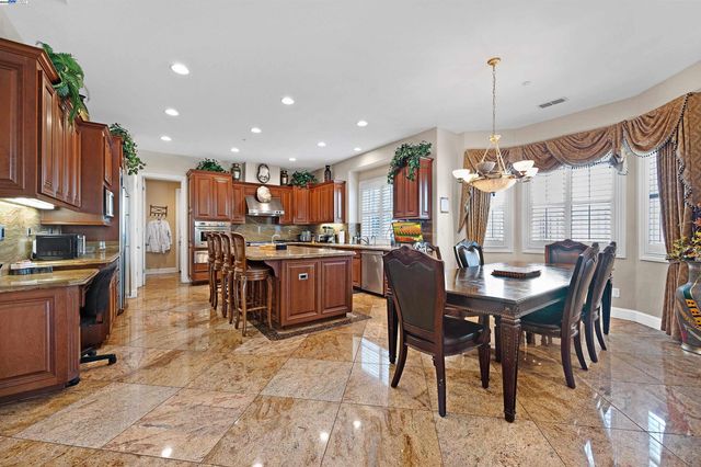 a kitchen with stainless steel appliances kitchen island granite countertop a table chairs and a refrigerator