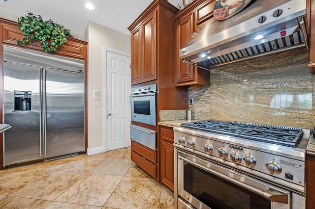 a view of a kitchen with stainless steel appliances granite countertop a stove a fridge and a shower