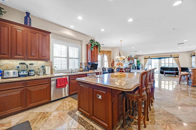 a kitchen with stainless steel appliances granite countertop a sink a stove a counter space and cabinets