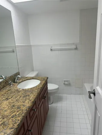 a bathroom with a granite countertop sink a toilet and bathtub