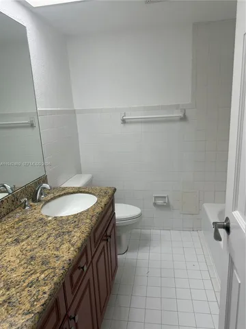 a bathroom with a granite countertop sink a toilet and bathtub