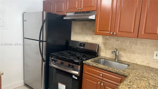 a kitchen with granite countertop a refrigerator stove and sink