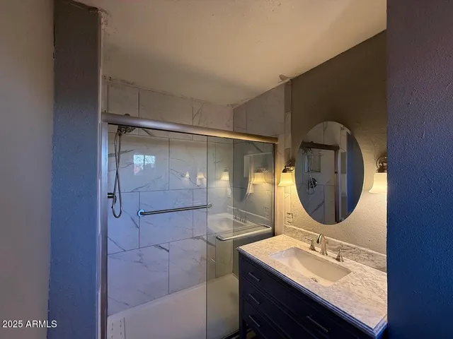 a bathroom with a granite countertop sink mirror and shower
