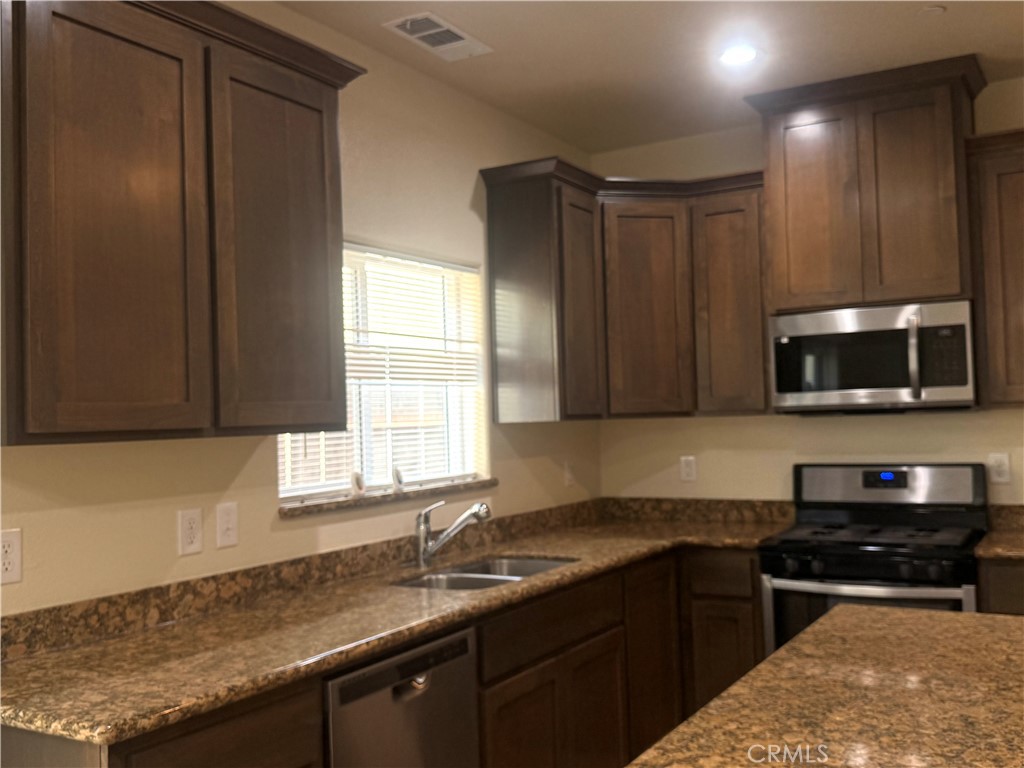 1339 Playa Del Rey Drive Merced, CA 95348 - Photo 9 of 48 a kitchen with granite countertop stainless steel appliances a sink window and cabinets