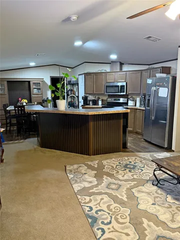 a kitchen with stainless steel appliances kitchen island granite countertop a refrigerator and a stove