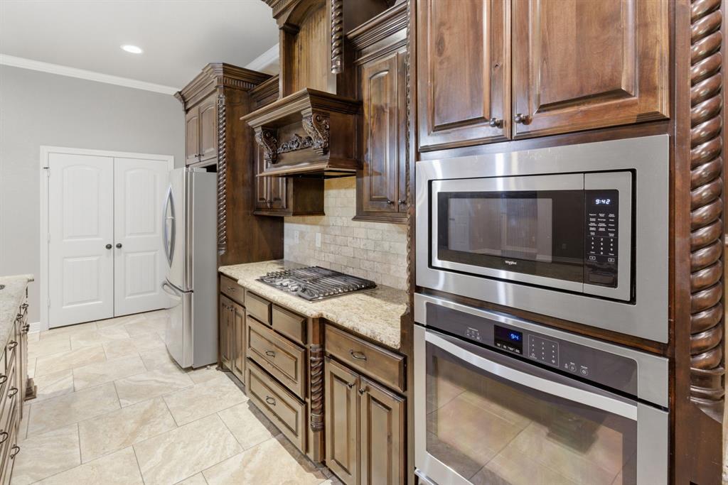 7765 Hickory Spring Lane Tyler, TX 75703 - Photo 21 of 38 Kitchen featuring rich wood cabinetry, granite countertops, tile backsplash, and stainless steel appliances including a built-in microwave, wall oven, and gas cooktop